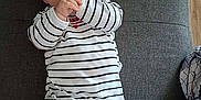 Bryana a rejoint le concours — aidez-le/la à gagner de superbes lots ! baby, infant, striped_clothing, onesie, cushion, gray, floor, wooden_floor, hand, face, lying_down, curious, child, indoors, footed_pajamas, person, sucking_fingers, cute, young_child, fabric
