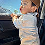 toddler, child, cap, brown_cap, car_interior, window, mesh_screen, sunlight, shadow, curious, standing, white_shirt, striped_shirt, young_child, side_profile, cute, expression, hand_on_window, casual_clothing, daylight