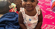 Nyla is registered to the contest to win money with this photo: toddler, child, smiling, headband, blue_headband, flower, pink_blanket, crown_pattern, stuffed_animal, brown_toy, blanket, indoor, portrait, happy, sitting, clothing, cute, baby, person, home