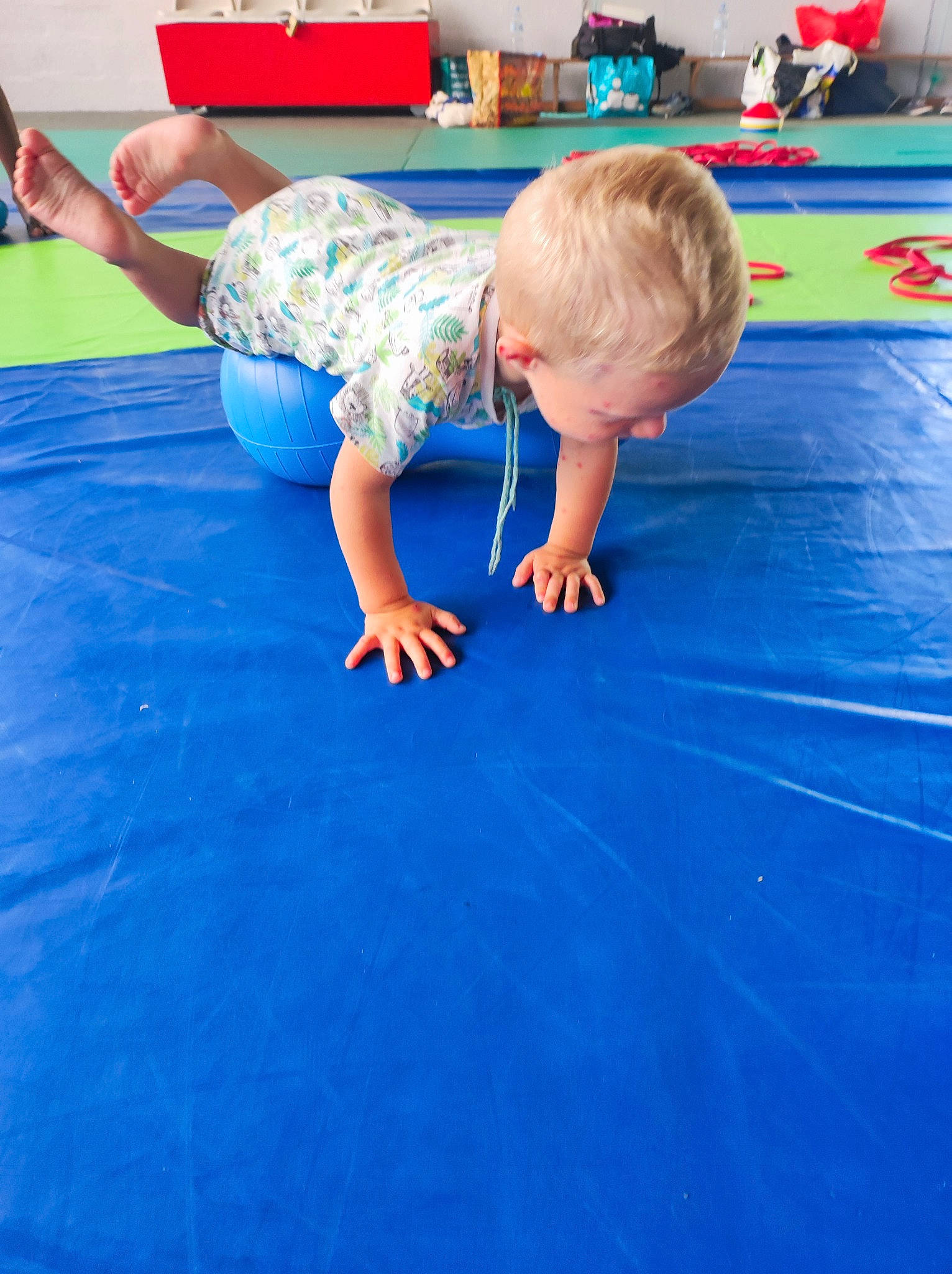 Manoé a rejoint le concours — aidez-le/la à gagner de superbes lots ! balance, barefoot, carpet, child, competition_event, electric_blue, floor, flooring, fun, grass, knee, leg, leisure, person, play, recreation, room, shorts, sitting, t_shirt