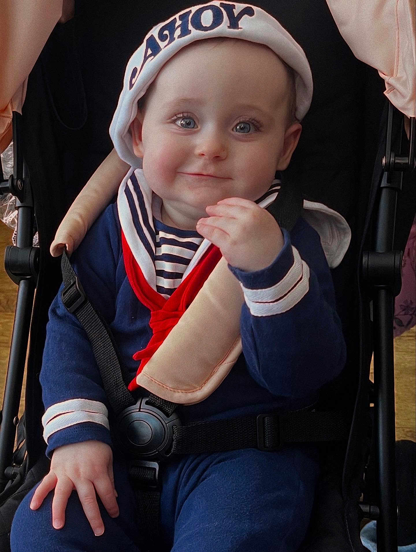Poppy joined the competition — help win amazing prizes! baby, child, sailor_hat, smile, blue_eyes, stroller, navy_outfit, red_scarf, seat_belt, cute, portrait, indoor, hand, face, person, clothing, infant, baby_clothes, happy, childhood