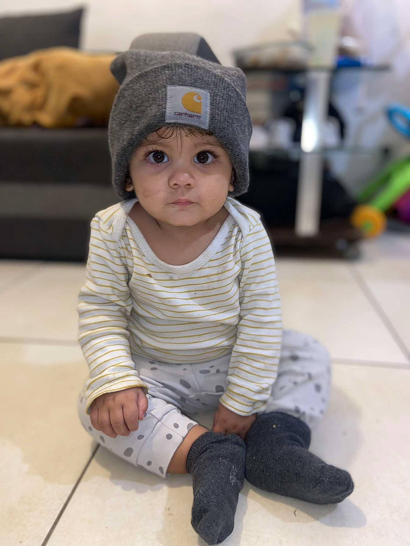 Kélya a rejoint le concours — aidez-le/la à gagner de superbes lots ! baby, baby_toddler_clothing, cap, cheek, child, face, fashion_accessory, floor, flooring, foot, fur, headgear, headwear, human_leg, knee, person, sitting, skin, sleeve, toddler