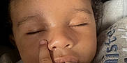 Asad is registered to the contest to win money with this photo: baby, child, curly_hair, fingers_in_mouth, sleeping, blanket, cozy, close_up, face, peaceful, infant, hand, skin, mouth, nose, eyelids, pacifier_clip, soft_texture, indoor, portrait