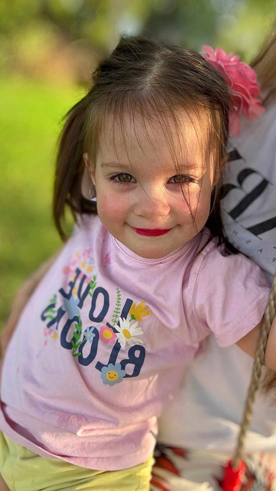 Sofia participe au concours pour gagner de l'argent avec cette photo : child, girl, smile, face, hair, pink_shirt, flower, outdoor, green_background, portrait, sunlight, happy, cute, person, toddler, playful, closeup, casual_clothing, nature, summer