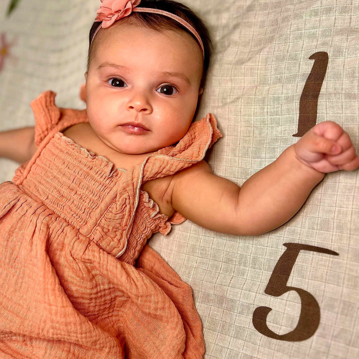 Athena is registered to the contest to win money with this photo: accessories, arm, baby, bodypart, clothing, face, finger, hand, happy, head, newborn, number, person, photography, portrait, sitting, sleeve, smile, symbol, text