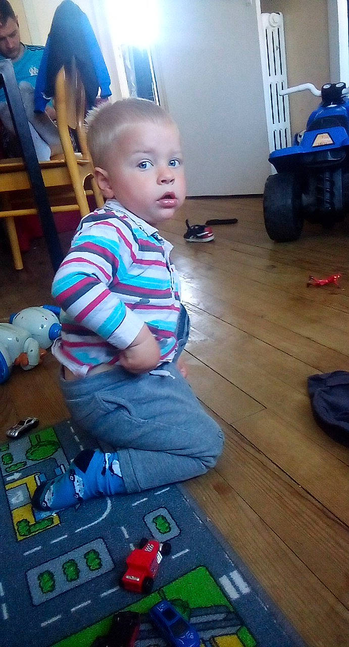 Brayan participe au concours pour gagner de l'argent avec cette photo : baby, baby_toddler_clothing, blue, chair, child, electric_blue, floor, flooring, fun, hardwood, lap, person, play, sitting, standing, surprise, t_shirt, technology, toddler, toy