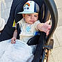 baby, blanket, cap, casual, child, clothing, comfort, curious, cute, hand, infant, outdoor, pavement, person, reaching, seat, stroller, sunlight, transport, young