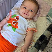 Romy participe au concours pour gagner de l'argent avec cette photo : baby, beads, blanket, child, clothing, comfort, cute, fabric, face, hand, happy, indoor, infant, orange, person, smile, stroller, toddler, toy, white