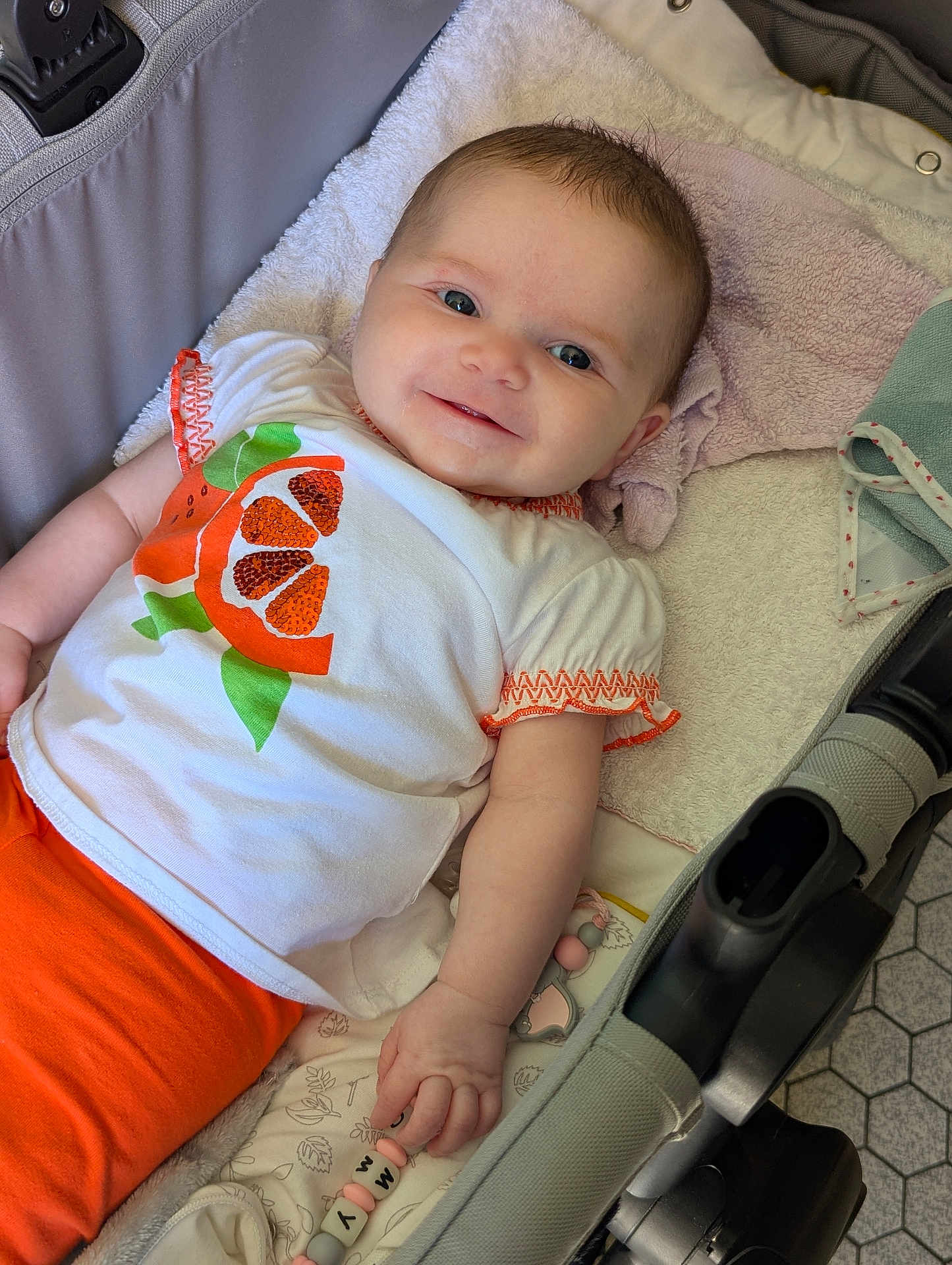 Romy participe au concours pour gagner de l'argent avec cette photo : baby, beads, blanket, child, clothing, comfort, cute, fabric, face, hand, happy, indoor, infant, orange, person, smile, stroller, toddler, toy, white