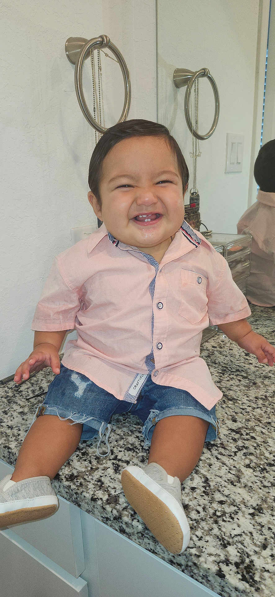Wayne joined the competition — help win amazing prizes! toddler, child, smiling, shirt, denim_shorts, shoes, countertop, bathroom, mirror, reflection, granite, cabinet, happy, cute, indoor, person, short_sleeve, casual_clothing, young_child, sitting