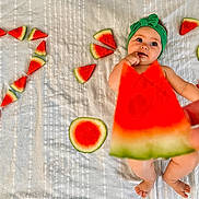 Eden a rejoint le concours — aidez-le/la à gagner de superbes lots ! baby, blanket, colorful, cute, expression, feet, fingers, food, fruit, green_headband, hand, infant, lying_down, playful, question_mark, skin, slice, striped, summer, watermelon