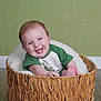 baby, smiling, basket, green_shirt, indoor, wooden_floor, blanket, cute, happy, child, infant, portrait, seated, cozy, homedecor, cheerful, one_person, looking_at_camera, light_skin, short_hair