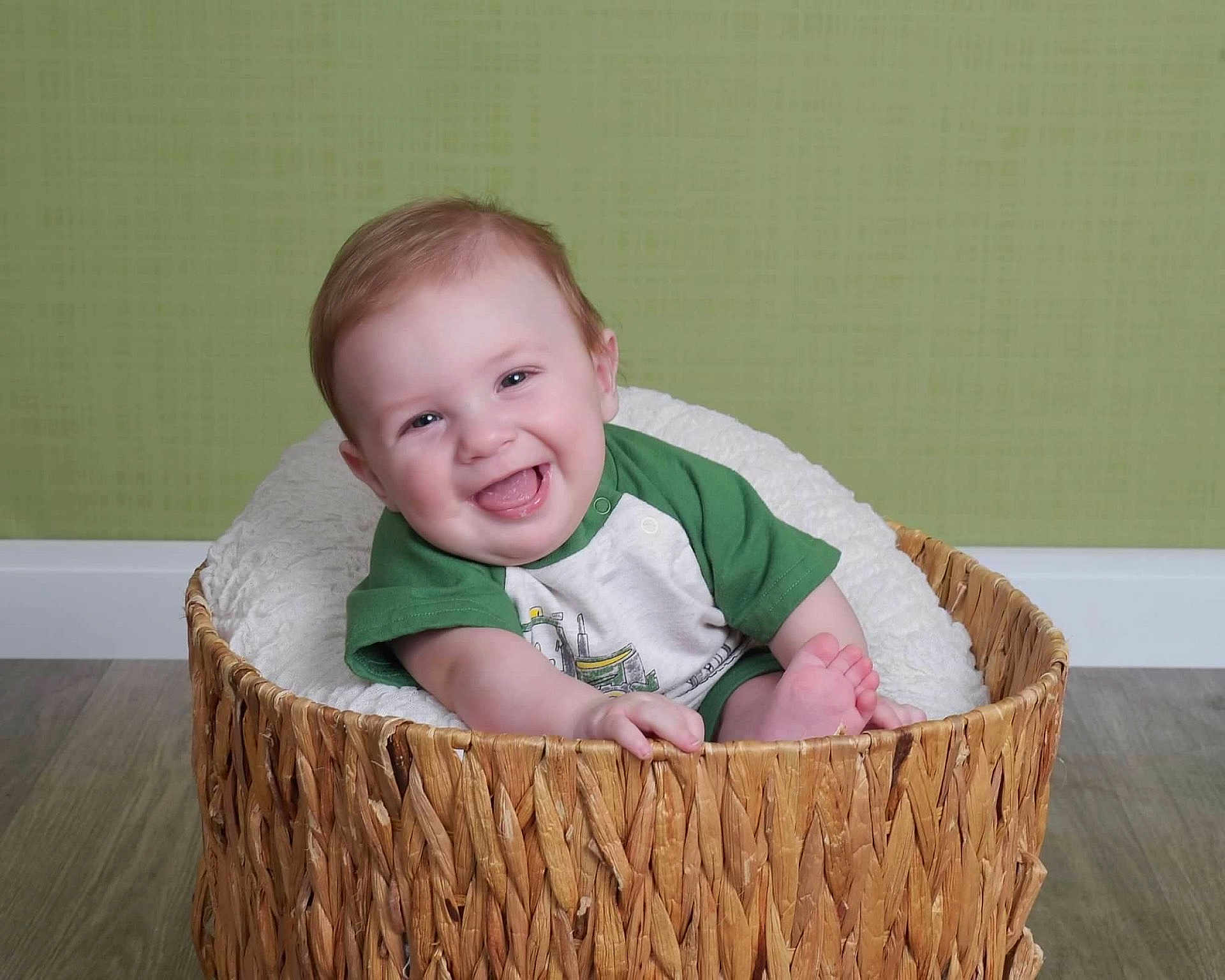 Owen joined the competition — help win amazing prizes! baby, smiling, basket, green_shirt, indoor, wooden_floor, blanket, cute, happy, child, infant, portrait, seated, cozy, homedecor, cheerful, one_person, looking_at_camera, light_skin, short_hair