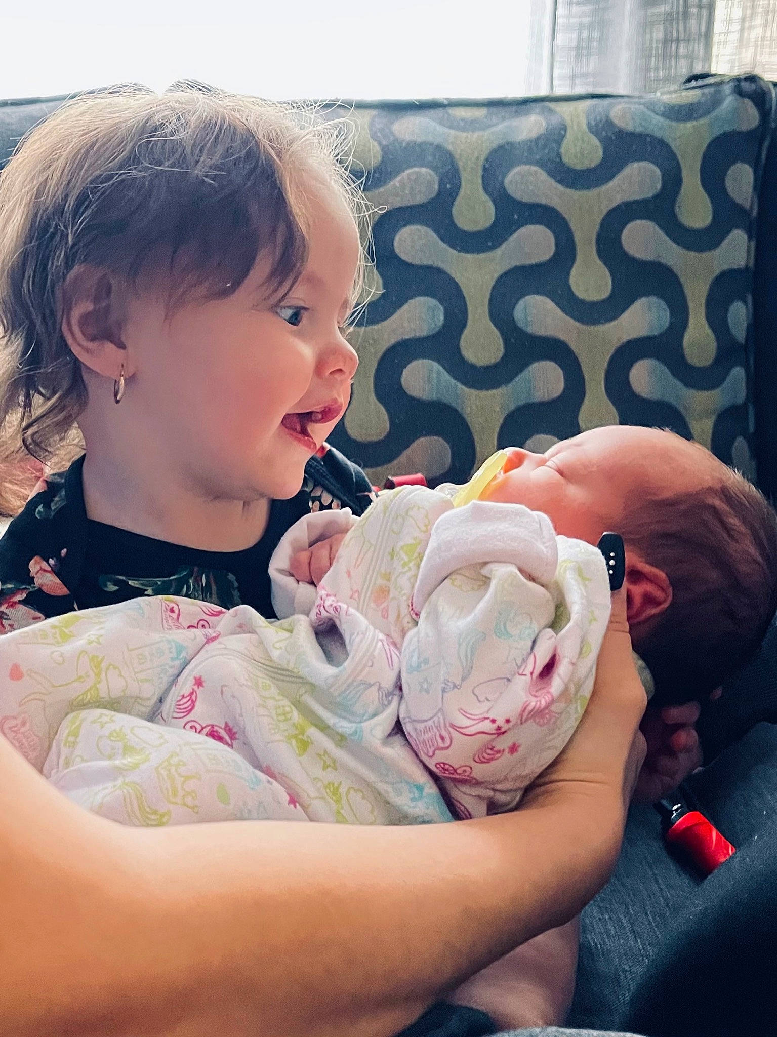 Carmella is registered to the contest to win money with this photo: baby, baby_products, baby_toddler_clothing, cheek, child, comfort, couch, eyelash, finger, fun, happy, mouth, nail, pattern, person, portrait_photography, sitting, skin, thigh, toddler