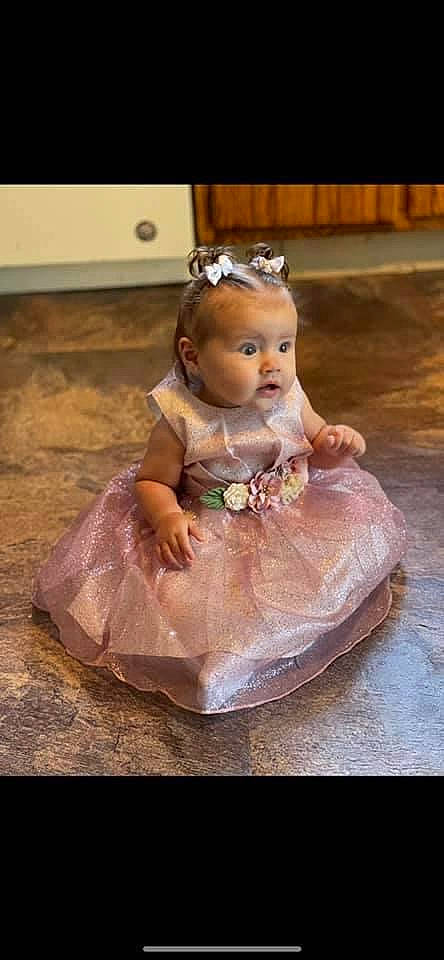 Camilla is registered to the contest to win money with this photo: baby, baby_toddler_clothing, bridal_accessory, cheek, child, clothing, dress, embellishment, flash_photography, floor, flooring, happy, headgear, headpiece, iris, jewellery, person, pink, smile, toddler