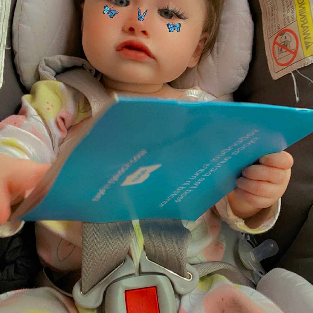 Maya joined the competition — help win amazing prizes! baby, book, couch, crib, cushion, doll, face, furniture, head, homedecor, infantbed, person, photography, portrait, publication, reading, text, toy, transportation, vehicle