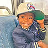 Lamont joined the competition — help win amazing prizes! child, smile, baseball_cap, jacket, blue_jeans, bus_seat, window, denim, happy, portrait, casual_wear, indoor, person, young_child, hat, seat, transport, public_transport, cute, joyful