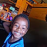 child, smiling, portrait, indoor, restaurant, happy, boy, casual, blue_shirt, face, hair, furniture, table, television, wood, arm, skin, eyes, mouth, light