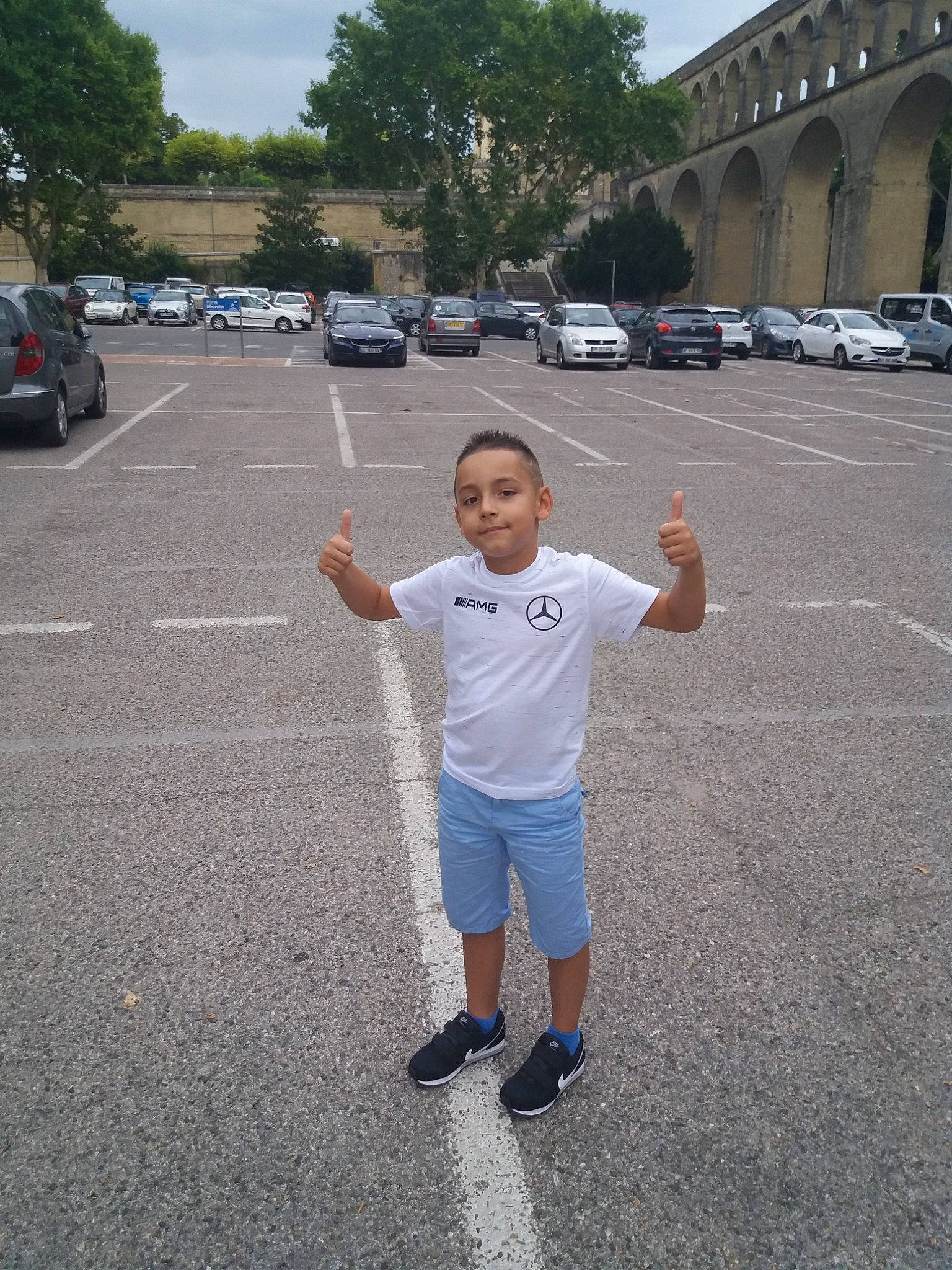 Hissane participe au concours pour gagner de l'argent avec cette photo : asphalt, car, family_car, fun, gesture, lane, pedestrian, person, road, shoe, sky, smile, street, t_shirt, tourism, vacation, vehicle, walking