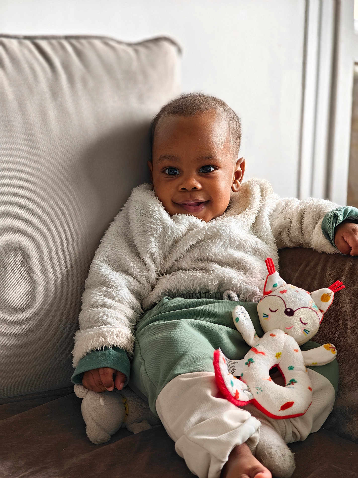 Muhammad a rejoint le concours — aidez-le/la à gagner de superbes lots ! baby, child, smiling, couch, plush_toy, soft_jacket, pants, indoor, cozy, relaxed, portrait, cute, infant, furniture, home, person, toy, comfort, warm, happy