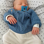 Sohan participe au concours pour gagner de l'argent avec cette photo : baby, newborn, sleeping, pacifier, blue_sweater, white_pants, hospital_wristband, star_pattern, blanket, infant, cozy, cute, child, resting, hand, face, soft, indoors, clothing, portrait