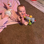 Skylar is registered to the contest to win money with this photo: baby, baby_clothing, candid, carpet, child, cozy, diaper, face, happy, home, indoor, infant, lying_down, pink_blanket, playroom, plush_toy, portrait, red_basket, smiling, teething_toy