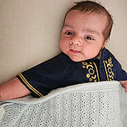 Rohan joined the competition — help win amazing prizes! baby, infant, blanket, blue_shirt, embroidered_clothing, face, skin, cute, lying_down, indoors, soft_texture, arm, head, expression, young_child, portrait, cozy, warm, fabric, resting