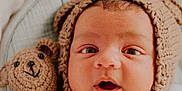 Rohan joined the competition — help win amazing prizes! baby, infant, knitted_hat, bear_ears, crocheted_teddy_bear, blanket, cozy, cute, wide_eyes, surprised_expression, soft_texture, portrait, child, newborn, indoors, warm, snuggled, sleeping_area, adorable, headwear