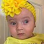 baby, child, yellow_headband, flower, mickey_mouse, minnie_mouse, yellow_shirt, earrings, face, portrait, cute, indoor, person, expression, apparel, headwear, young_child, looking_away, closeup, toddler