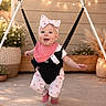 Alora Grace joined the competition — help win amazing prizes! baby, child, infant, smiling, headband, bib, baby_jumper, outdoor, plants, flowers, string_lights, concrete_floor, potted_plants, pink_clothing, happy, cute, sunlight, playful, person, bouncing
