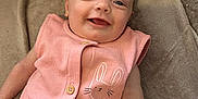 Millie-Mae is registered to the contest to win money with this photo: baby, infant, smiling, pink_outfit, bunny_design, blanket, couch, happy, face, head, arm, buttoned_clothing, soft_texture, indoor, cute, person, portrait, lying_down, child, cozy