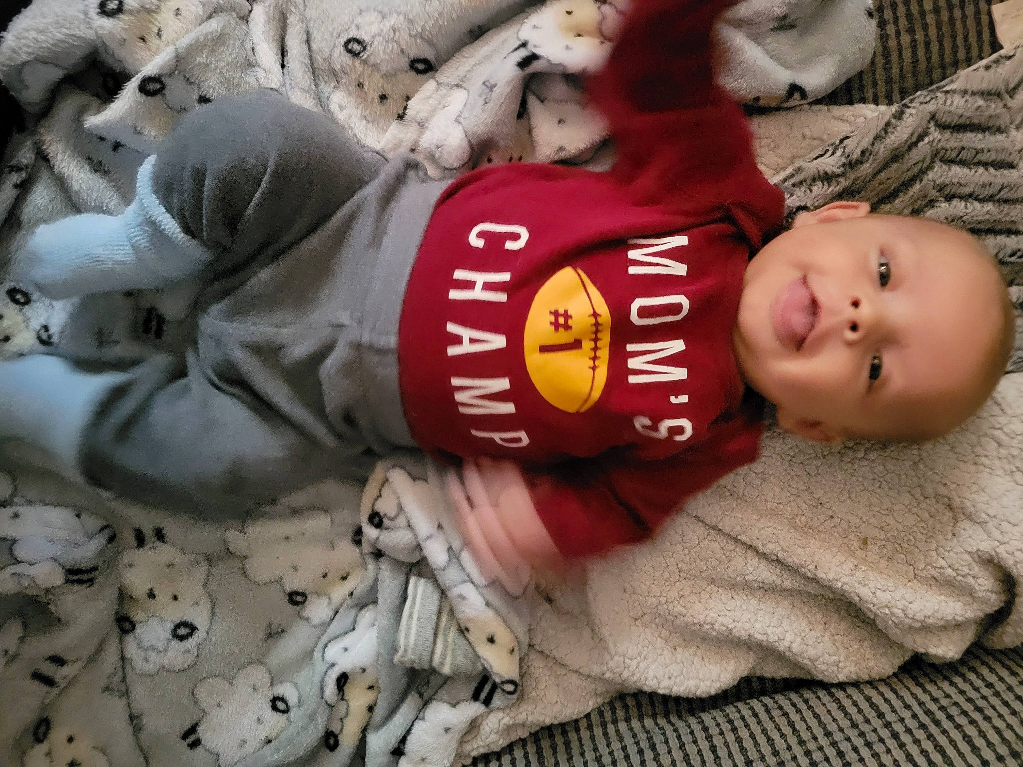 Ashton is registered to the contest to win money with this photo: baby, baby_toddler_clothing, carmine, child, comfort, headgear, person, personal_protective_equipment, sitting, sleeve, smile, toddler, winter, wood