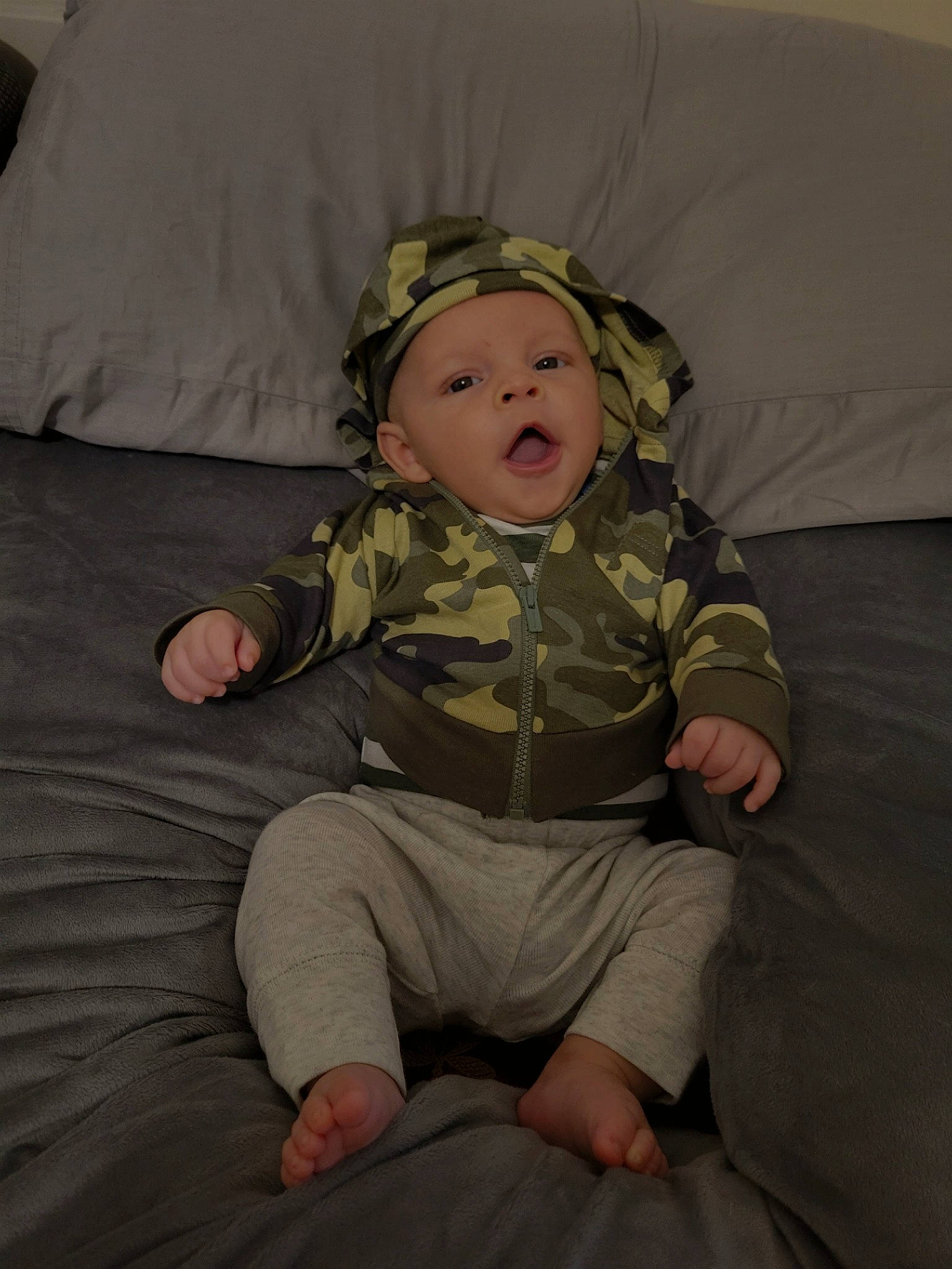 Ashton is registered to the contest to win money with this photo: baby, baby_toddler_clothing, cheek, child, comfort, eye, flooring, fun, grass, head, headwear, lap, linens, pattern, person, personal_protective_equipment, room, sitting, sleeve, textile