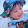 baby, child, infant, smiling, happy, portrait, face, eyes, mouth, hat, bucket_hat, animal_print, colorful, clothing, sleeve, hand, indoors, close_up, photography, joyful