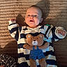 Brooks joined the competition — help win amazing prizes! baby, infant, child, smiling, portrait, indoors, lying_down, striped_clothing, teddy_bear, stuffed_animal, toy, blanket, textured_background, leopard_print, bedding, warm_lighting, cozy, raised_arm, hand, face