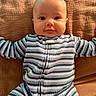 Brooks is registered to the contest to win money with this photo: baby, child, infant, portrait, face, smiling, eyes, lying_down, couch, sofa, cushion, striped_clothing, jumpsuit, knitwear, blue, white, brown, indoors, cozy, photography