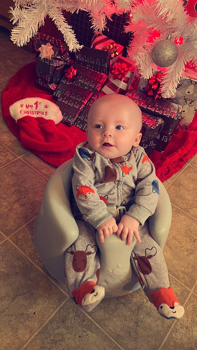 Micah is registered to the contest to win money with this photo: baby, baby_toddler_clothing, carmine, child, christmas, christmas_eve, christmas_ornament, costume_hat, event, fictional_character, happy, hat, head, holiday, lap, ornament, person, red, sitting, sleeve
