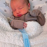 Wallen is registered to the contest to win money with this photo: newborn, baby, sleeping, blanket, pillow, pacifier, clothing, infant, cozy, soft, hand, face, peaceful, indoors, cute, child, resting, star_pattern, fabric, bundle