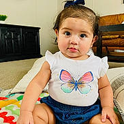 Emma joined the competition — help win amazing prizes! baby, child, infant, sitting, indoor, play_mat, butterfly_print, white_shirt, denim_shorts, blue_bow, cute, curious_eyes, chubby_cheeks, living_room, couch, carpet, pillow, furniture, person, portrait
