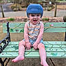 barefoot, bench, child, cute, daylight, garden, grass, happy, helmet, ladybug, outdoor, painted_bench, playful, portrait, sitting, smiling, spider, summer_clothing, toddler, vines