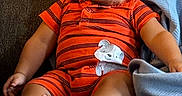 Kamari joined the competition — help win amazing prizes! baby, child, infant, pouty_face, orange_clothing, striped_clothing, elephant_patch, couch, gray_fabric, blanket, sitting, indoors, cute, expression, barefoot, chubby_cheeks, short_hair, relaxed, home, comfort