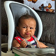 Kamari joined the competition — help win amazing prizes! baby, high_chair, child, pouty_face, striped_clothing, indoor, couch, blanket, teddy_bear_pattern, furniture, infant, seat, expression, cute, portrait, home, young_child, person, sitting, modern