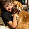 Lilly joined the competition — help win amazing prizes! person, dog, golden_retriever, hugging, smiling, indoor, couch, brown_hair, black_shirt, pet, happy, cozy, furniture, lantern, decor, relaxed, close_up, friendship, warm_lighting, home