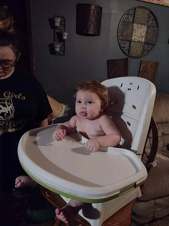 Silas is registered to the contest to win money with this photo: baby, bathing, chair, cheek, child, comfort, dishware, event, fun, hair, mouth, person, picture_frame, plate, purple, room, serveware, sitting, skin, tableware