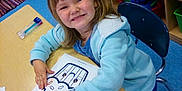 Serenity joined the competition — help win amazing prizes! child, smiling, coloring, crayons, table, classroom, drawing, art_supplies, sitting, toy_storage, shelf, blue_jacket, happy, preschool, education, indoor, person, young_child, activity, creative