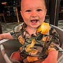 baby, child, smiling, happy, high_chair, shirt, lemon_pattern, indoor, person, face, cute, seated, clothing, infant, portrait, baby_clothes, furniture, hand, eyes, mouth