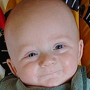 William is registered to the contest to win money with this photo: baby, infant, face, smile, closeup, child, young, cute, eyes, skin, expression, portrait, head, clothing, green, background, happy, person, indoors, young_child