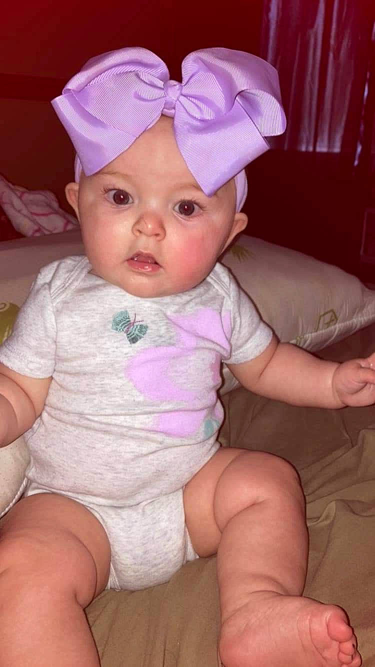 Harper is registered to the contest to win money with this photo: baby, baby_toddler_clothing, cap, cheek, eye, eyelash, finger, happy, headgear, headwear, leg, lip, magenta, mouth, person, pink, purple, skin, sleeve, thigh