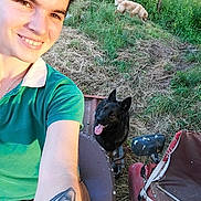 Malaya a rejoint le concours — aidez-le/la à gagner de superbes lots ! person, smile, tattoo, dog, black_dog, light_colored_dog, grass, outdoor, farm_equipment, greenery, sunlight, happy, pet, animal, nature, fence, selfie, casual_clothing, short_sleeve, tongue_out