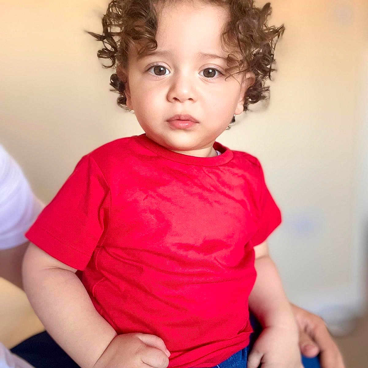 Hasan is registered to the contest to win money with this photo: baby, blonde, brownhair, clothing, curlyhair, face, hair, head, pants, person, photography, portrait, sad, sitting, sleeve, t_shirt